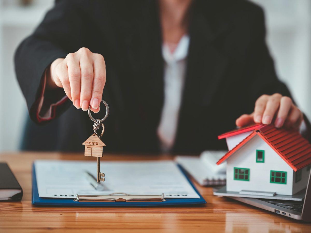 Real estate agent with house plans and keys in hand.